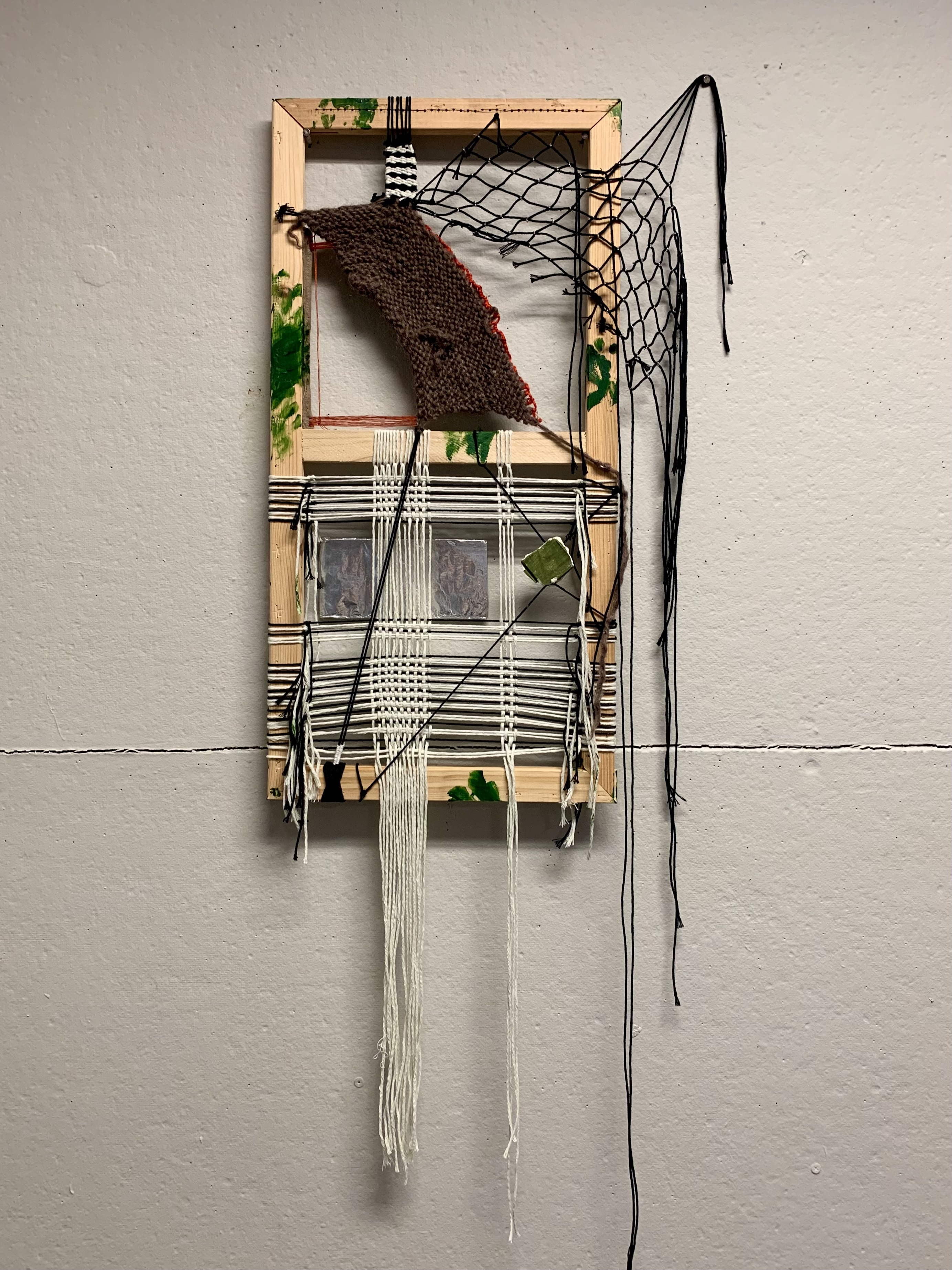 a wooden frame with knitted and woven layers of cord.